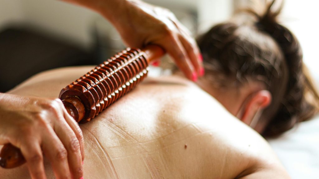 Close-up of a massage using a wooden roller for relaxation therapy.