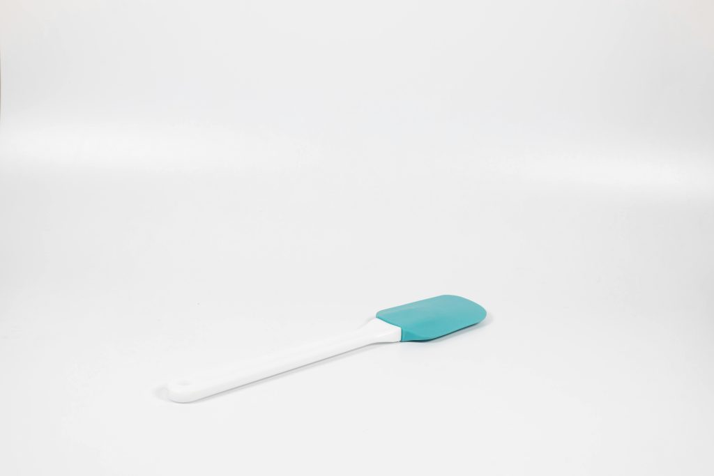 A minimalist shot of a blue and white silicone spatula on a white background.