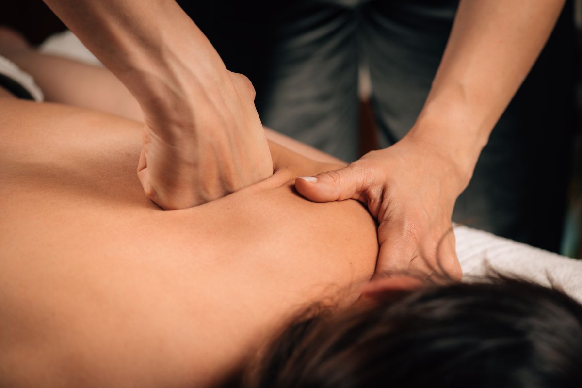 Terapeut izvodi Deep Tissue masažu leđa snažnim pritiskom šake i palca
