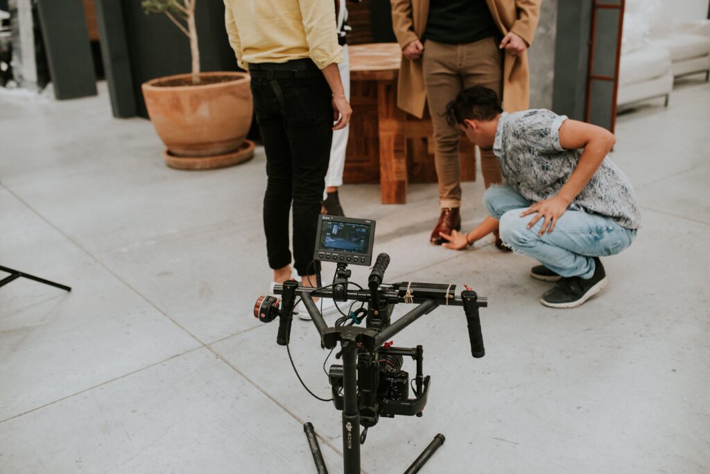 Film crew adjusting settings on a movie set indoors. Camera and people involved.