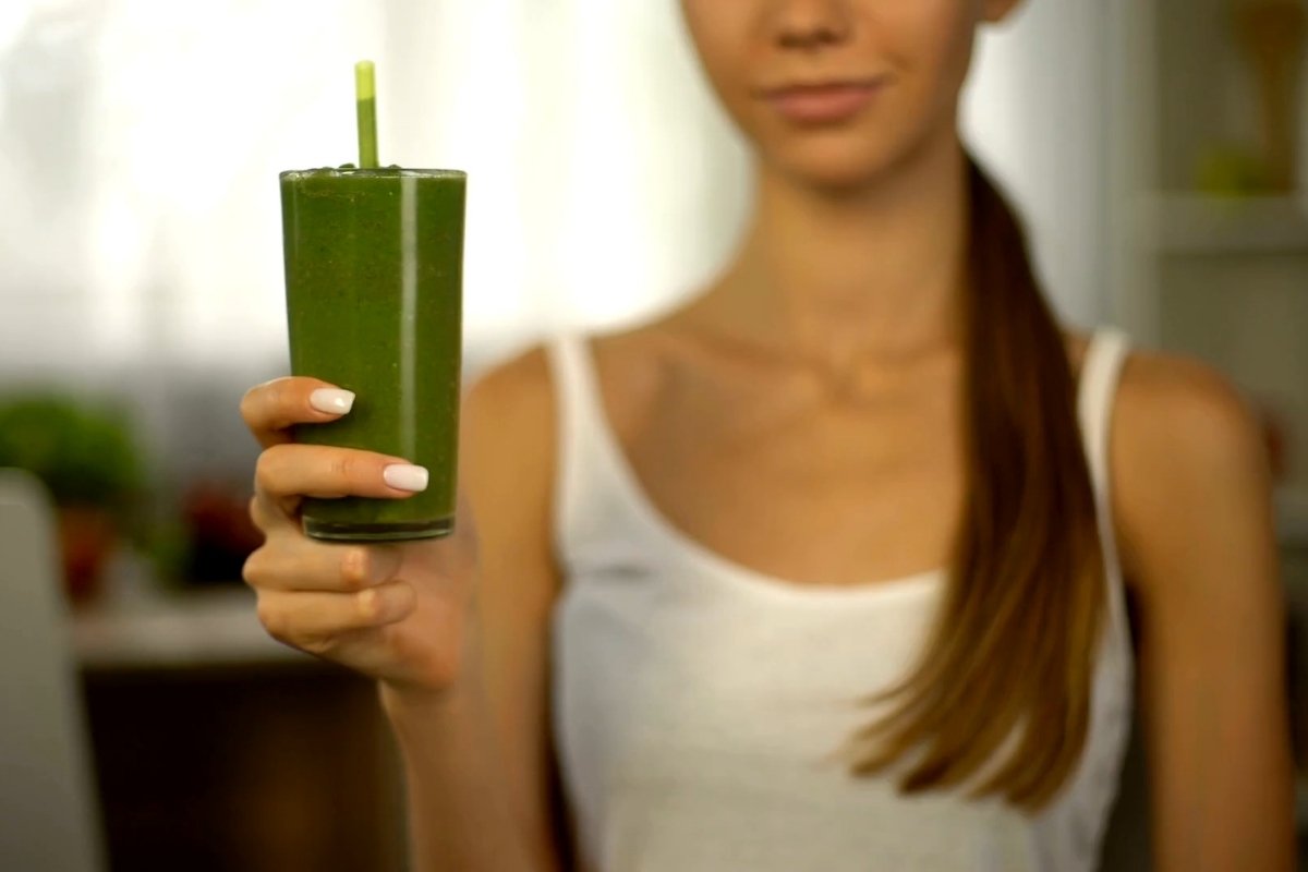 djevojka drži u ruci čašu sa zelenim smoothijem